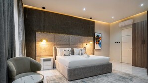 A modern bedroom with a large bed, bedside tables, a chair, and a rug. - George Residence Parkview (Lagos)