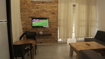 A living room with a wooden wall, a flat-screen TV, a wooden coffee table, and a sofa.