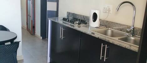 A compact kitchen with dark cabinets, a gas stove, a built-in oven, and a sink.