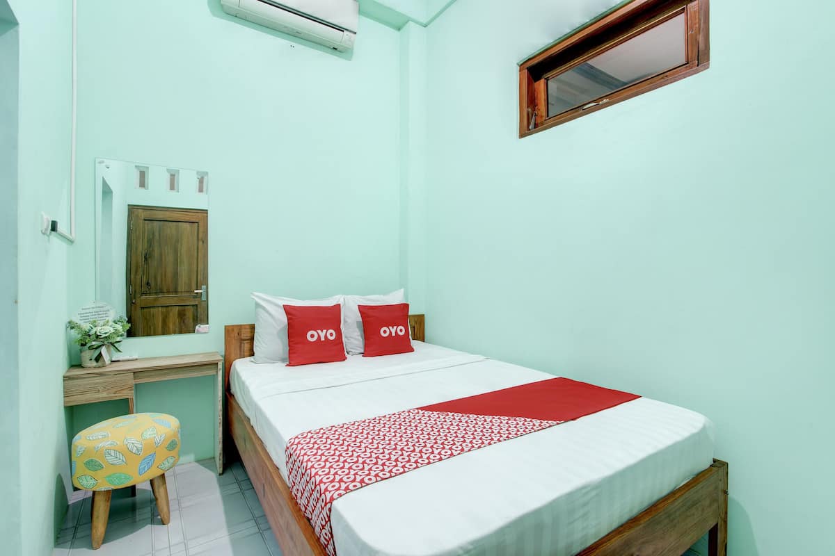Un dormitorio con cama, escritorio, silla y ventana.