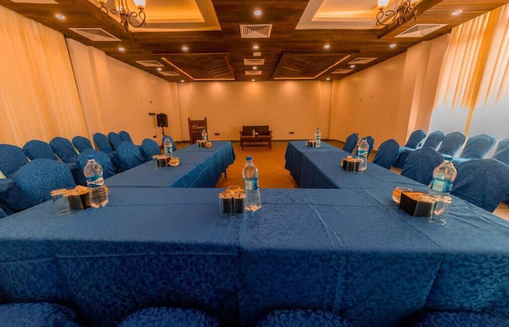 A conference room with blue upholstered chairs and tables, equipped with water bottles and glasses.