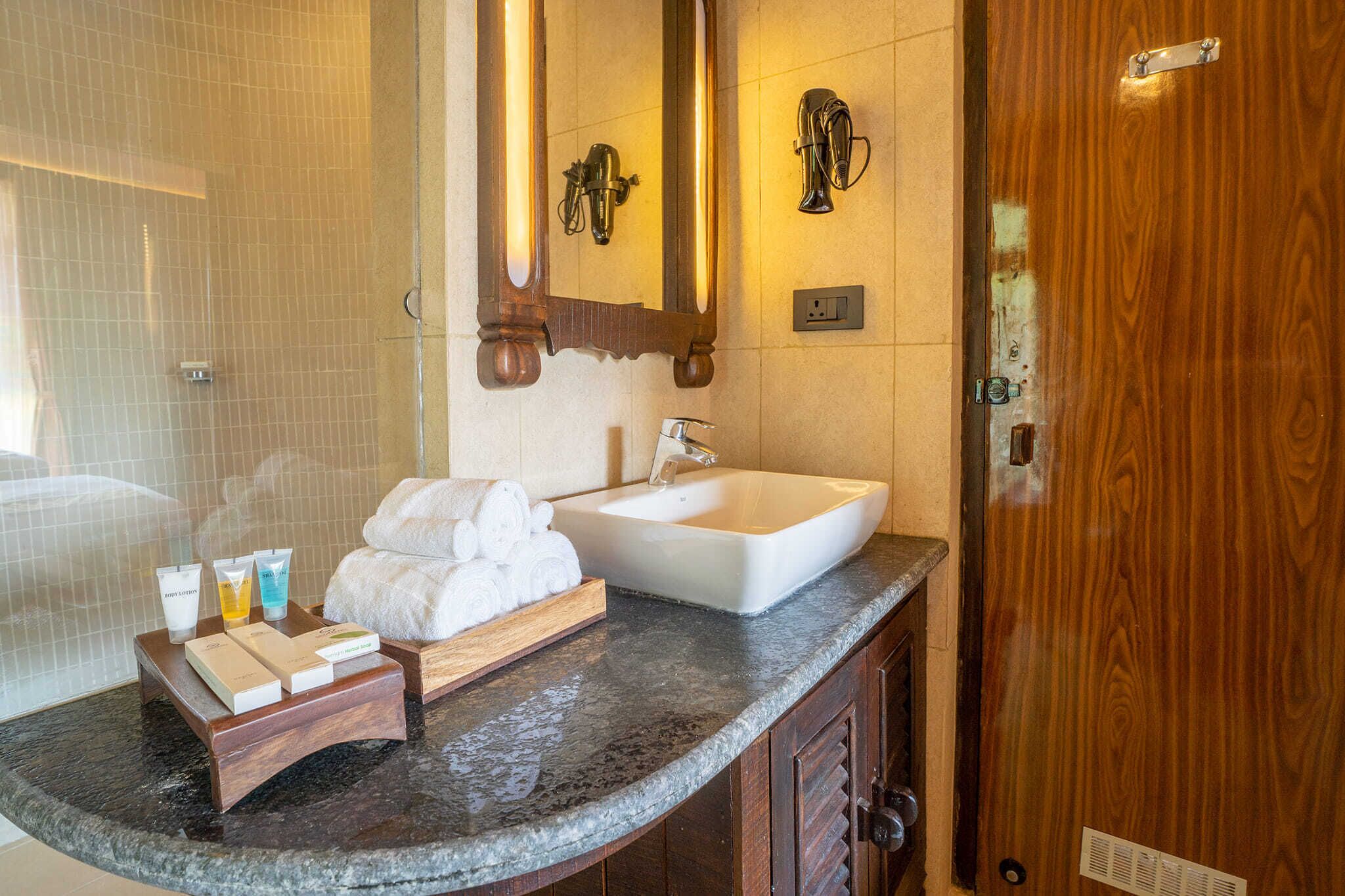 A bathroom with a marble countertop, a white sink, a wooden vanity, and a large mirror.