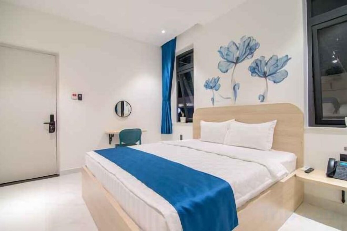 A hotel room with a bed, a desk, a chair, and a window.