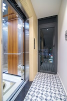 Un pasillo con piso estampado, un panel de madera y una puerta de cristal que da a una habitación.