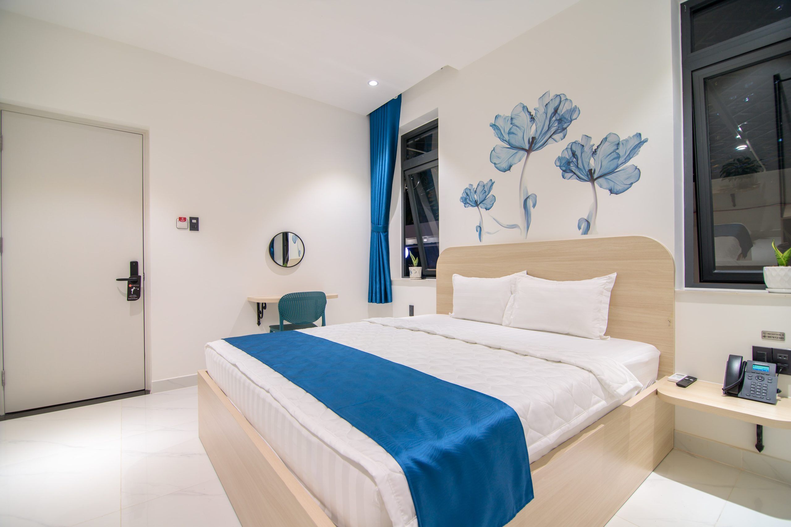 Una habitación de hotel moderna con una cama grande, un escritorio con teléfono y una ventana con vistas.