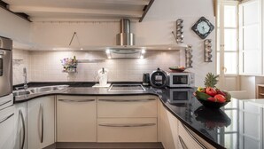 A modern kitchen with white cabinets, stainless steel appliances, and a black countertop.