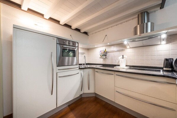A modern kitchen with white cabinetry, stainless steel appliances, and a black countertop. - Appartamento (Cagliari)