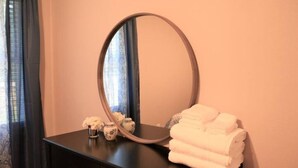 A bathroom with a round mirror, a black vanity, and a stack of white towels.