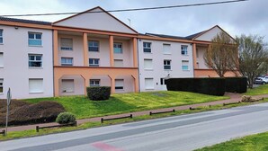 Um edifício residencial de vários andares com telhado plano, várias janelas e um gramado bem cuidado.