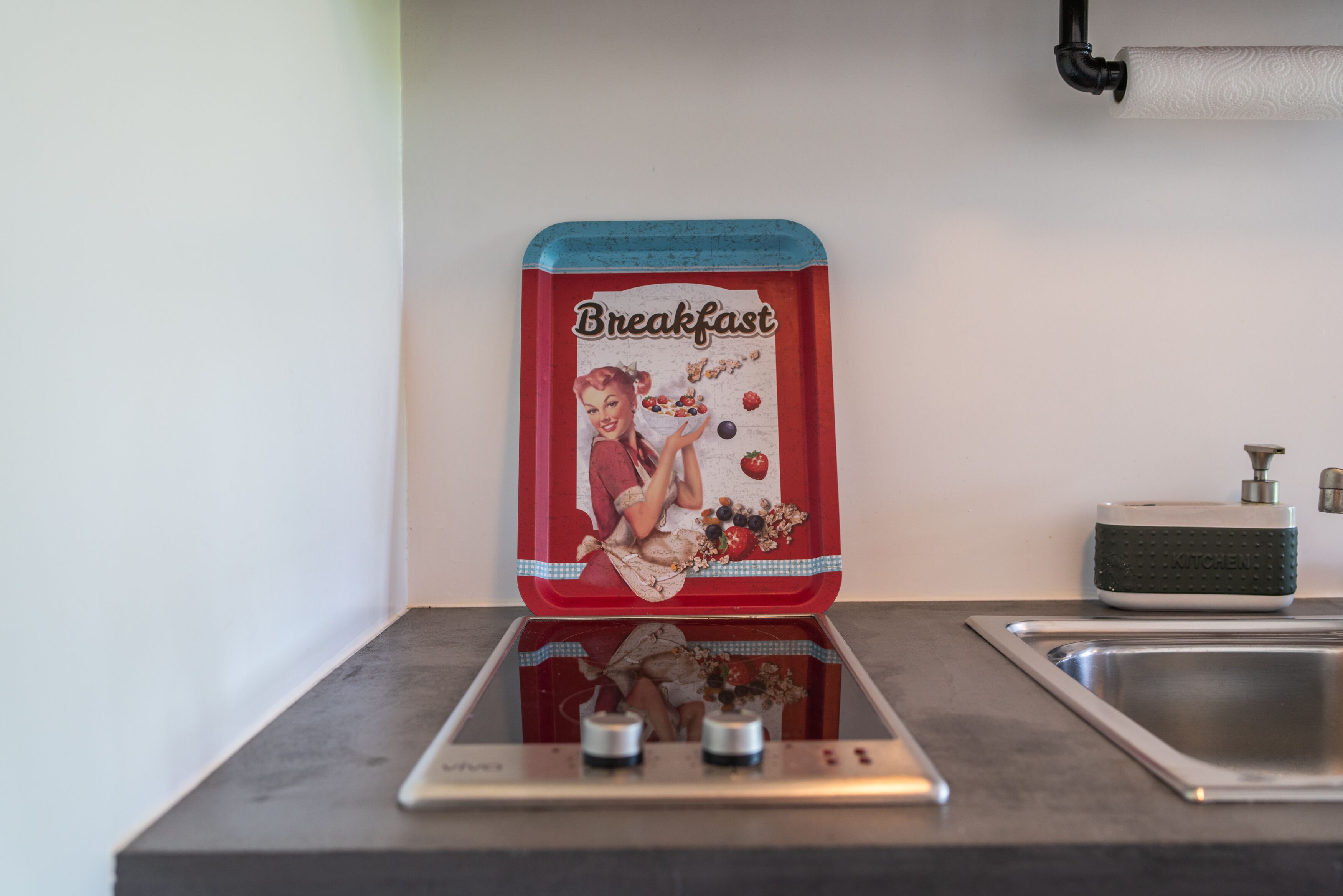 A kitchen with a vintage breakfast-themed container on the countertop, a modern faucet, and a sink.
