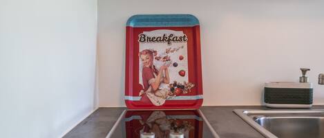 A kitchen with a vintage breakfast-themed container on the countertop, a modern faucet, and a sink.