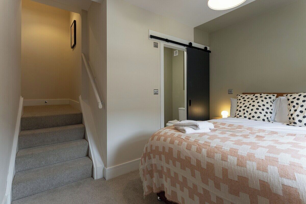 Une chambre à coucher avec un lit, un escalier et une porte de salle de bain.