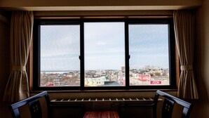 A room with a large window, a wooden table, and two chairs. - Tabist Hotel Nemuro Kaiyoutei (Nemuro)