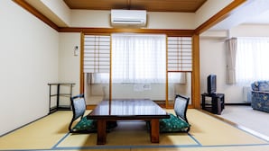 A traditional Japanese room with tatami flooring, a low table with cushions, sliding shoji doors, and a television on a small stand. - Tabist Hotel Nemuro Kaiyoutei (Nemuro)