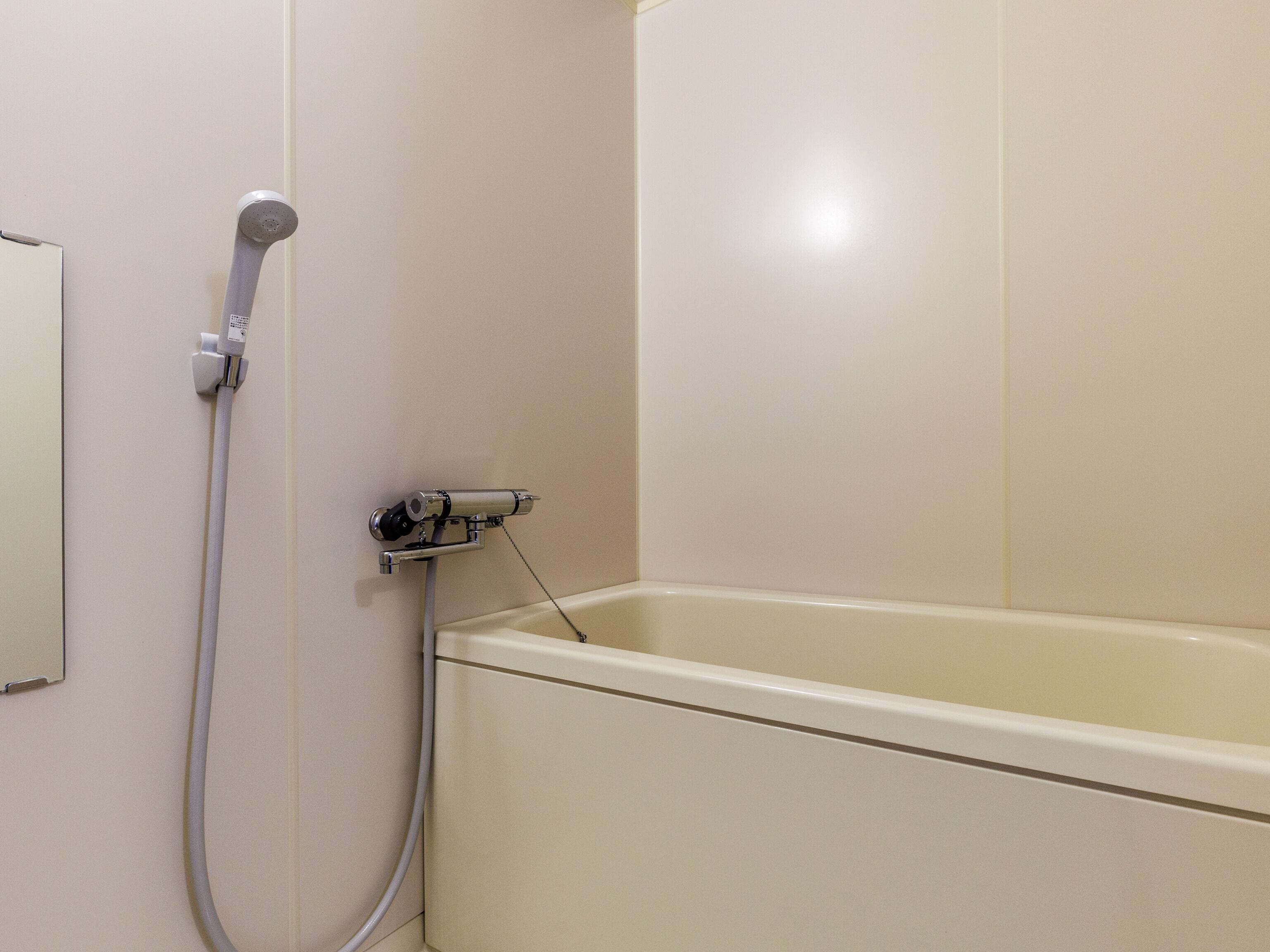 Ein Badezimmer mit Badewanne, Duschkopf und einer wandmontierten Bedienkonsole.