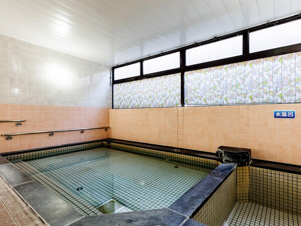Una piscina con azulejos, una pared revestida de azulejos y un ventanal con un diseño colorido.