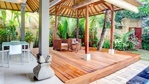 Ein überdachter Außenbereich mit Holzdeck, Sitzgelegenheiten und einem Tisch.