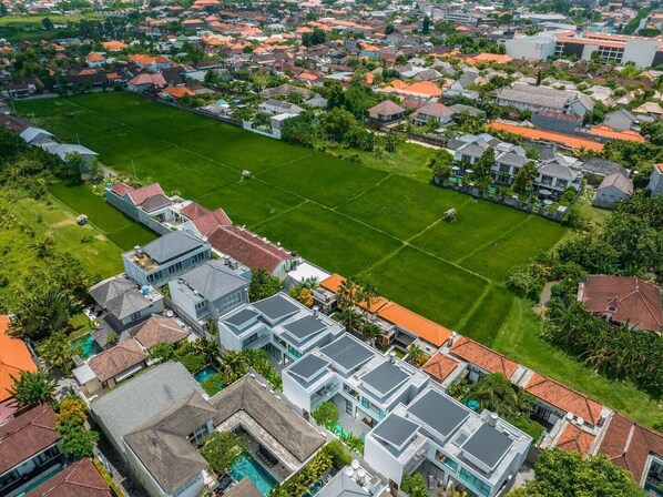 An aerial view of a residential area with a large green field, modern houses, and a swimming pool. - Sitara Villas Seminyak (Seminyak)