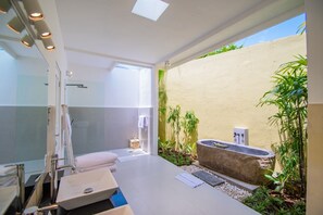 A modern bathroom with a glass shower enclosure, a large sink, and a stone basin. - Sitara Villas Seminyak (Seminyak)