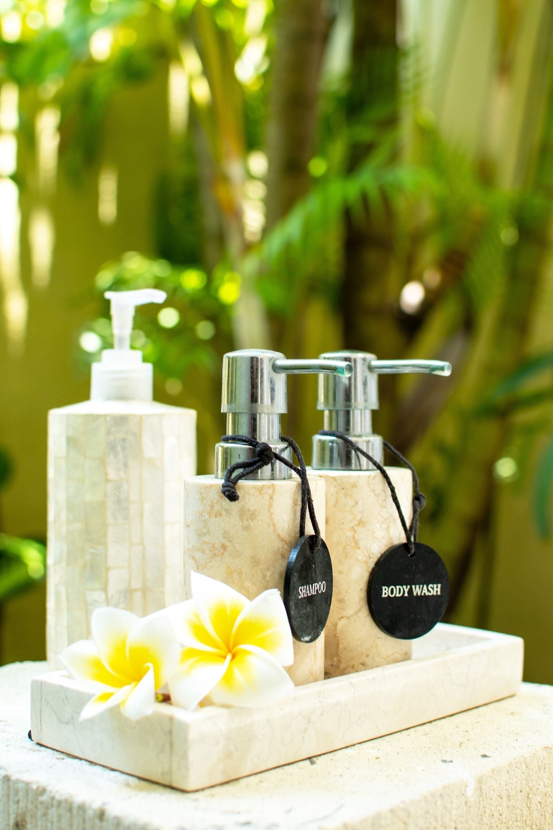 A set of toiletries on a marble surface with a tropical background.