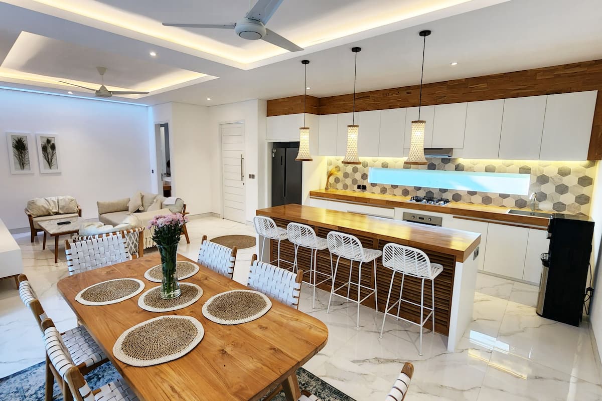 A modern kitchen with a central island, white cabinetry, and a hexagonal tile backsplash.