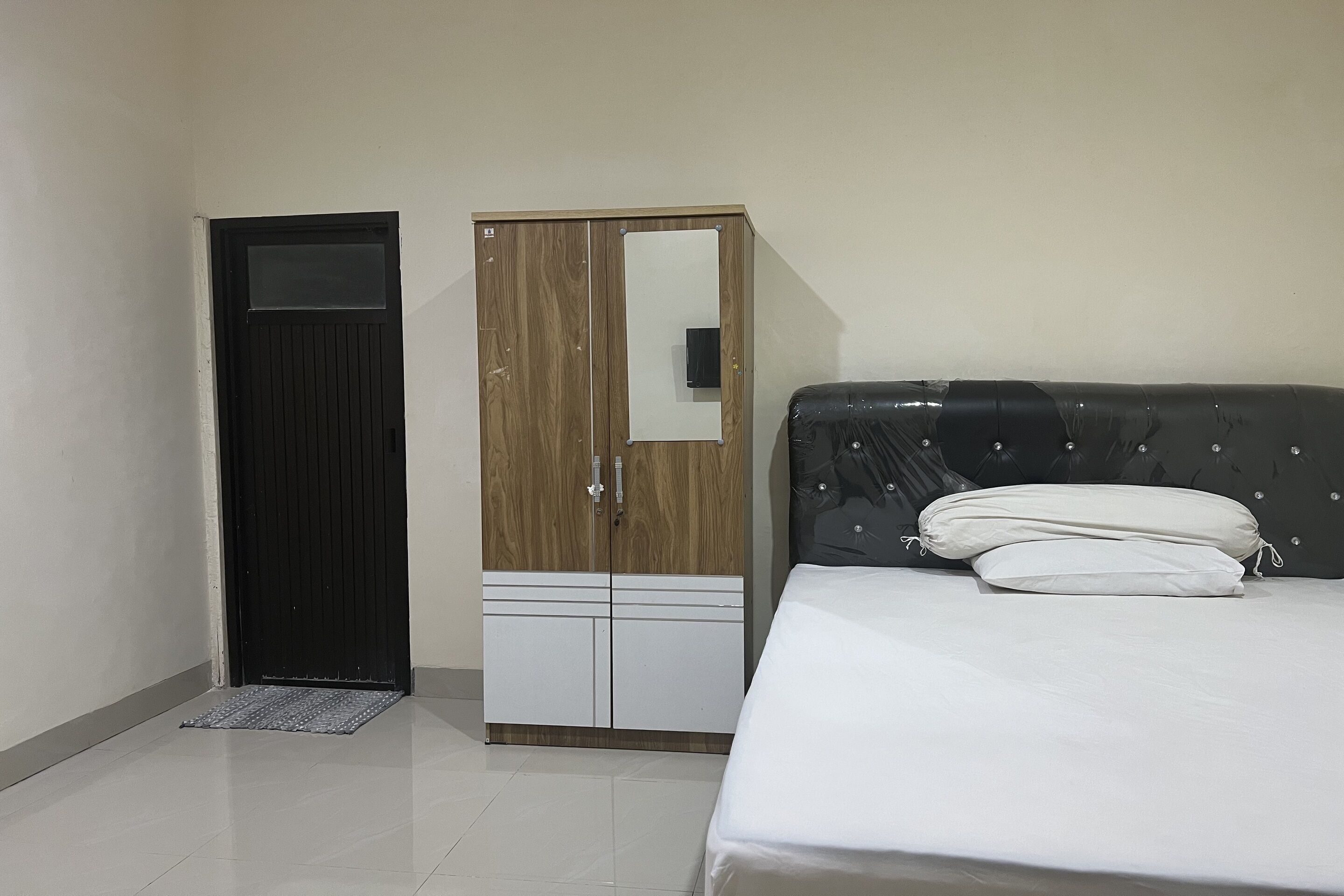 A room with a bed, a wardrobe, and a door.