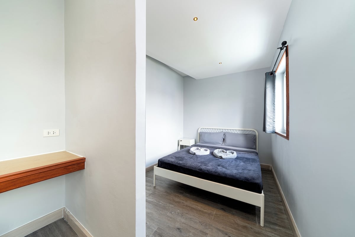 A bedroom with a bed, bedside table, and a window.