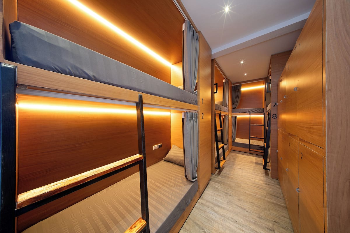 A corridor with bunk beds, wooden lockers, and a wooden floor.