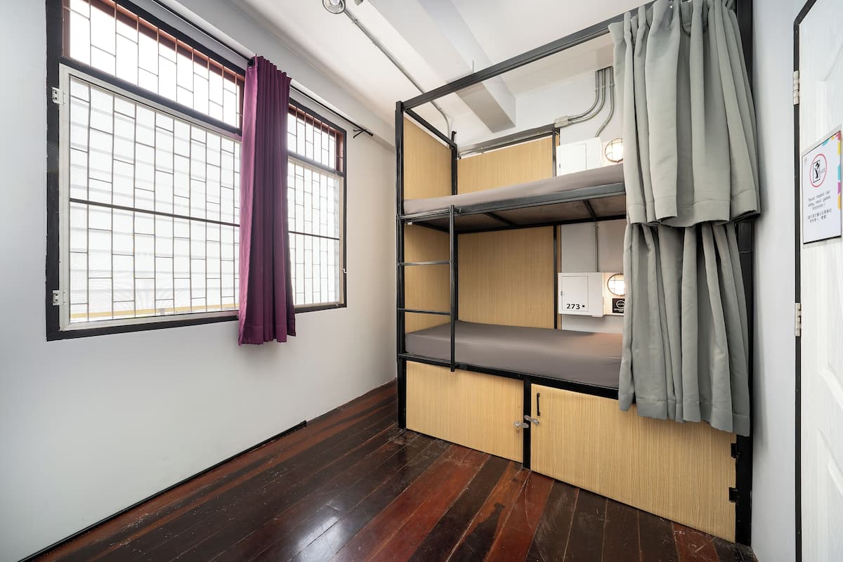 A bunk bed room with a window, curtains, and a door.