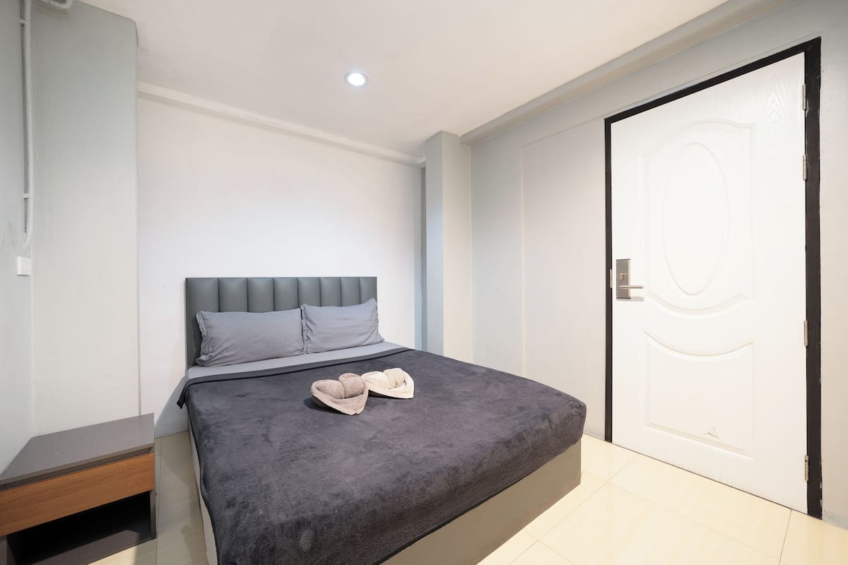 A bedroom with a bed, a nightstand, and a door.