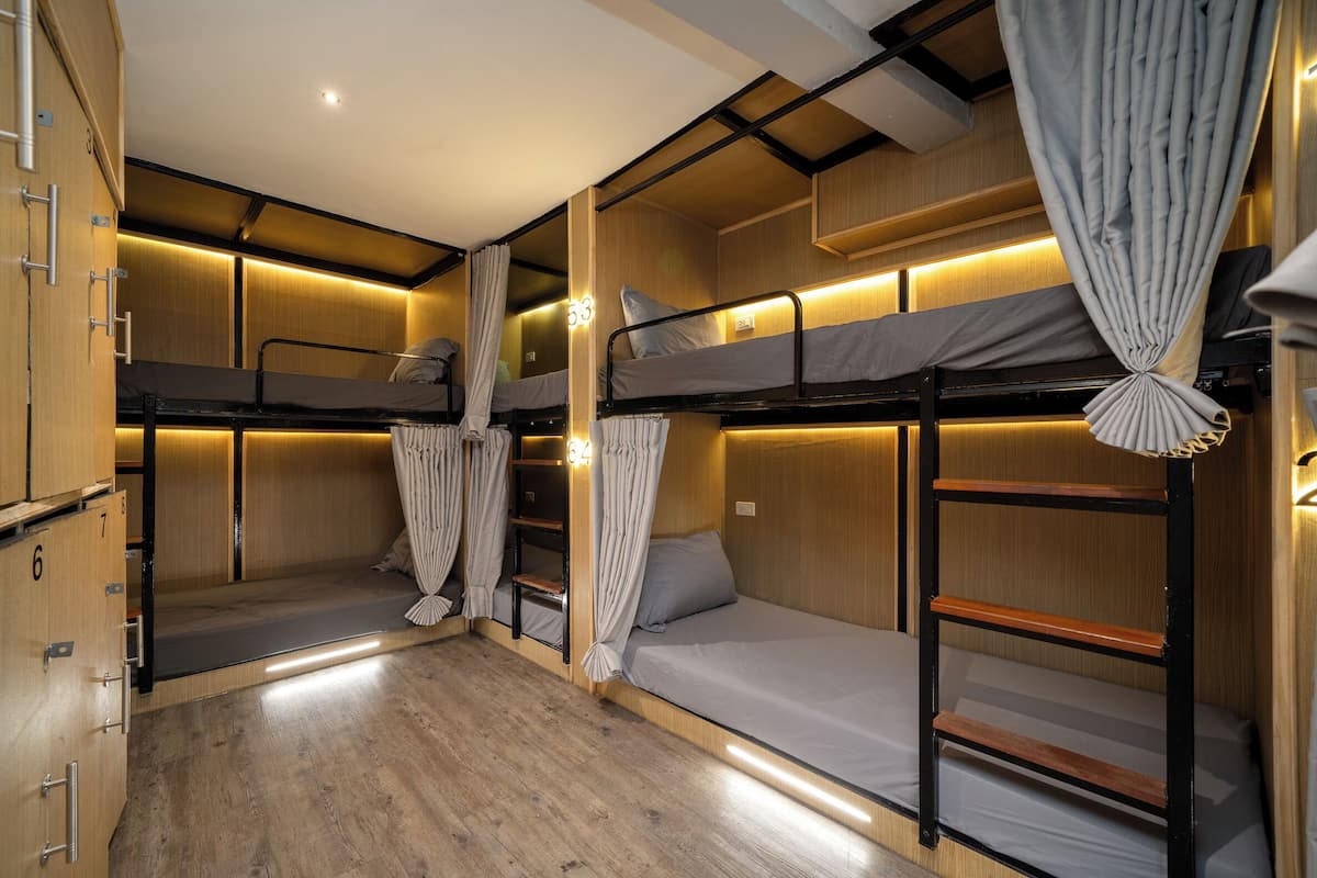 A bunk room with wooden walls, bunk beds, and a small wardrobe with numbered compartments.