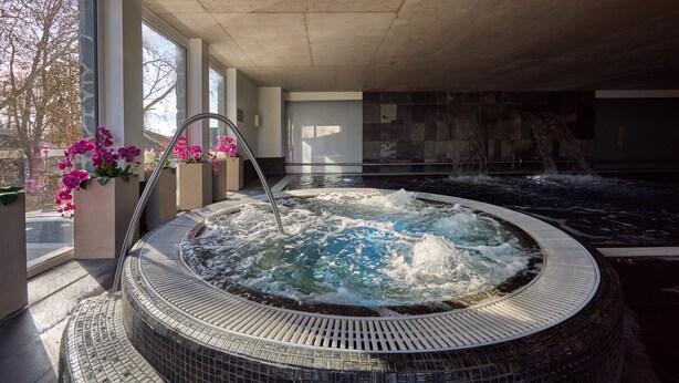 Ein Whirlpool mit gefliestem Beckenrand und einer Metallarmatur.