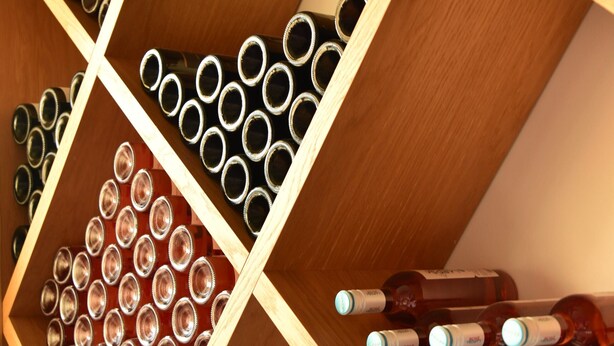 Ein Weinkühler mit mehreren Reihen Flaschen und leeren Weinkelchen.