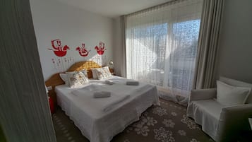Un dormitorio con cama, una silla, una ventana con cortinas y una pared con detalles decorativos rojos.