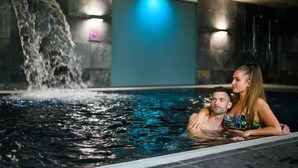 Ein Paar in einem Pool mit Wasserfall und einem Verbotsschild.