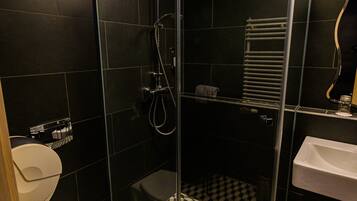 A bathroom with a glass-enclosed shower, a toilet, and a sink.