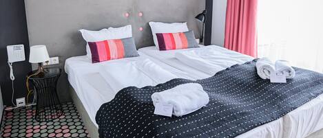 A hotel room with a large bed, a nightstand with a lamp, a telephone, and a patterned floor.