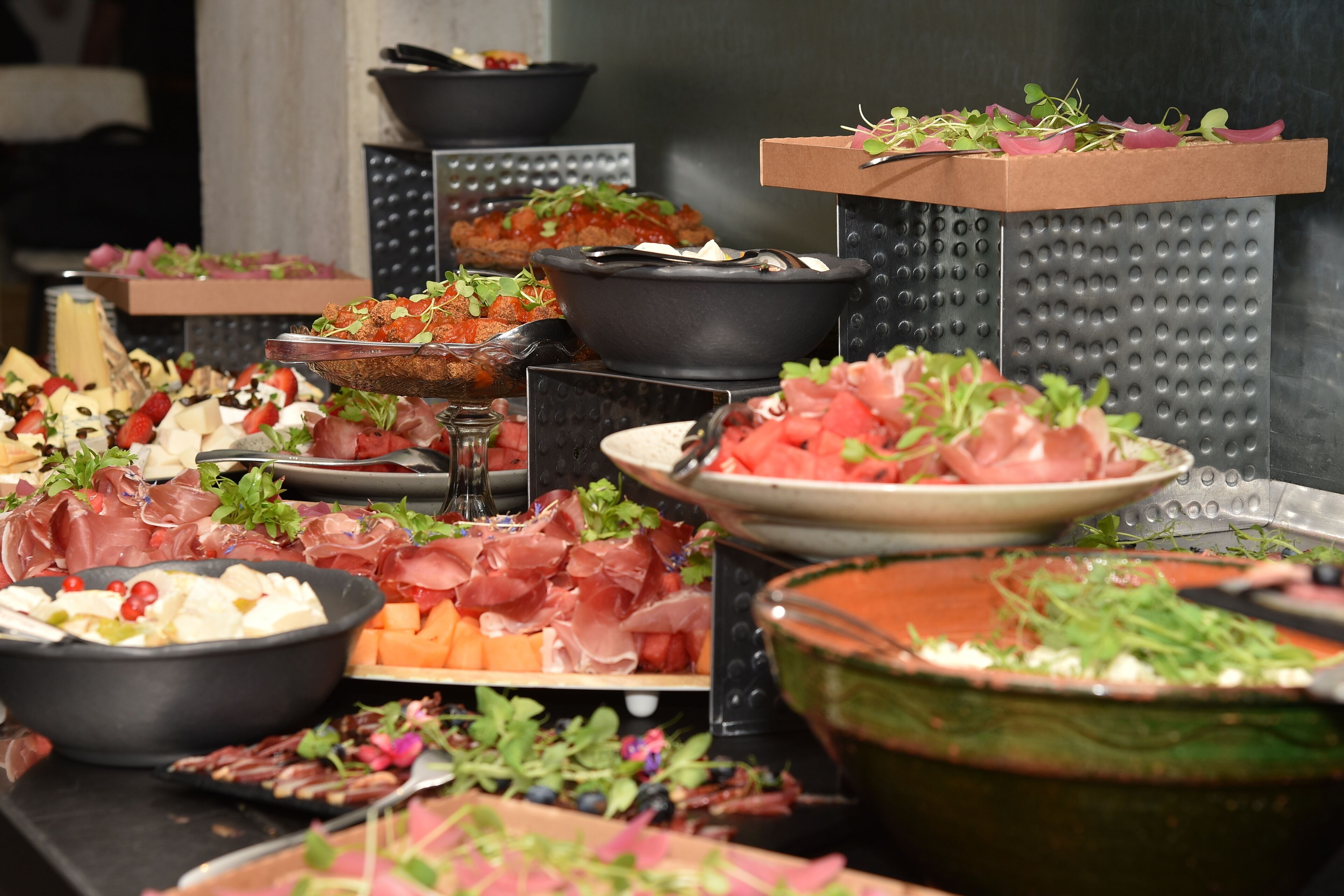 A buffet with various food items including meats, cheeses, and fruits.