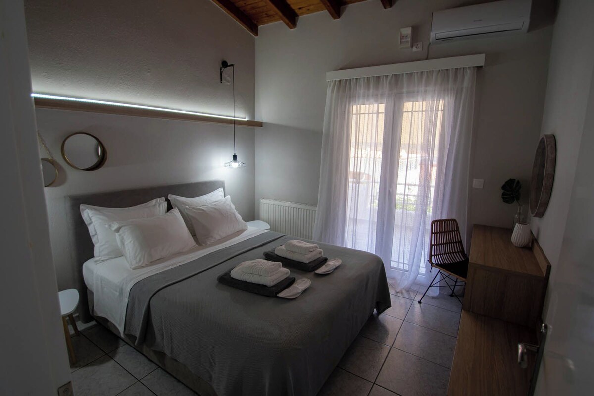 A bedroom with a bed, bedside tables, a chair, a radiator, and a window with curtains.