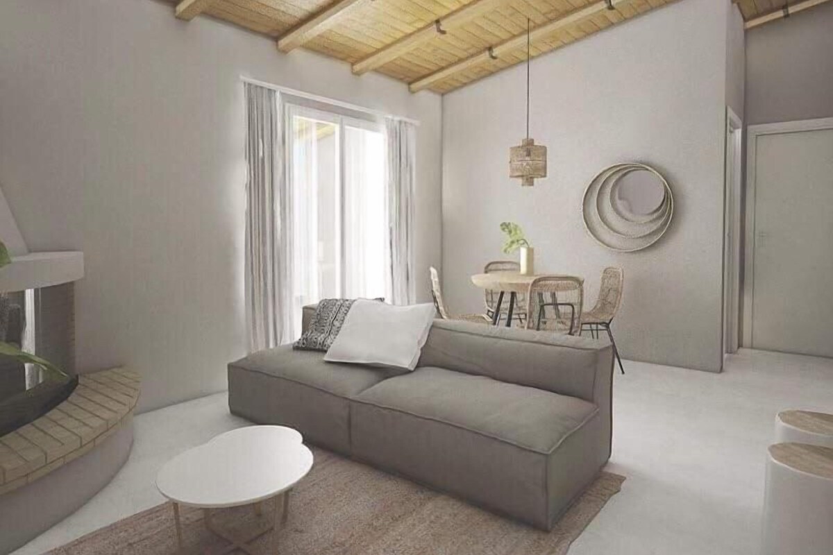 A modern living room with a grey sofa, a round coffee table, and a dining area with chairs and a table.