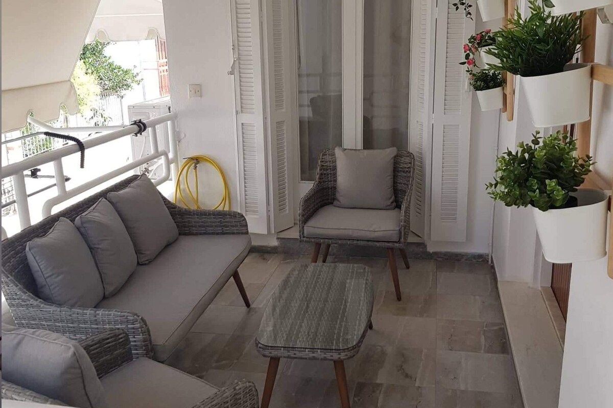 A balcony with wicker furniture, a chair, and potted plants.