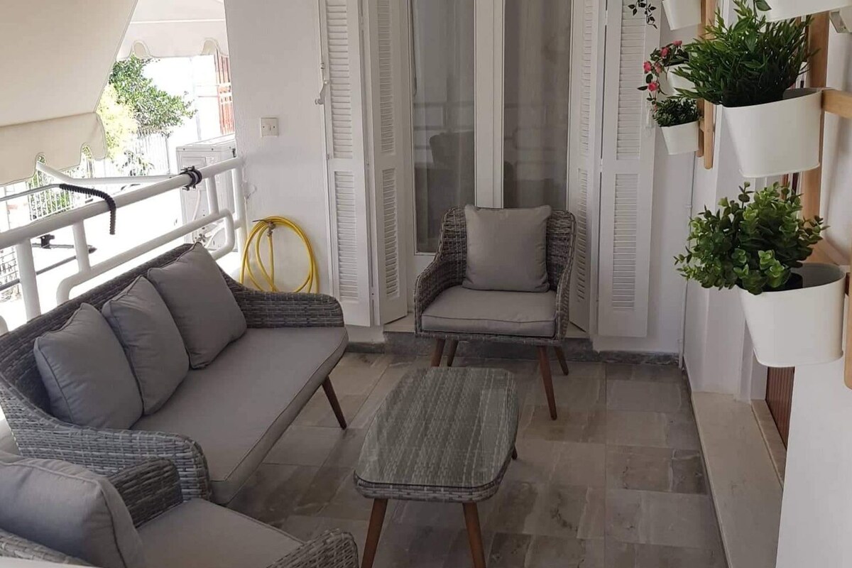 A balcony with wicker furniture, a chair, and potted plants.