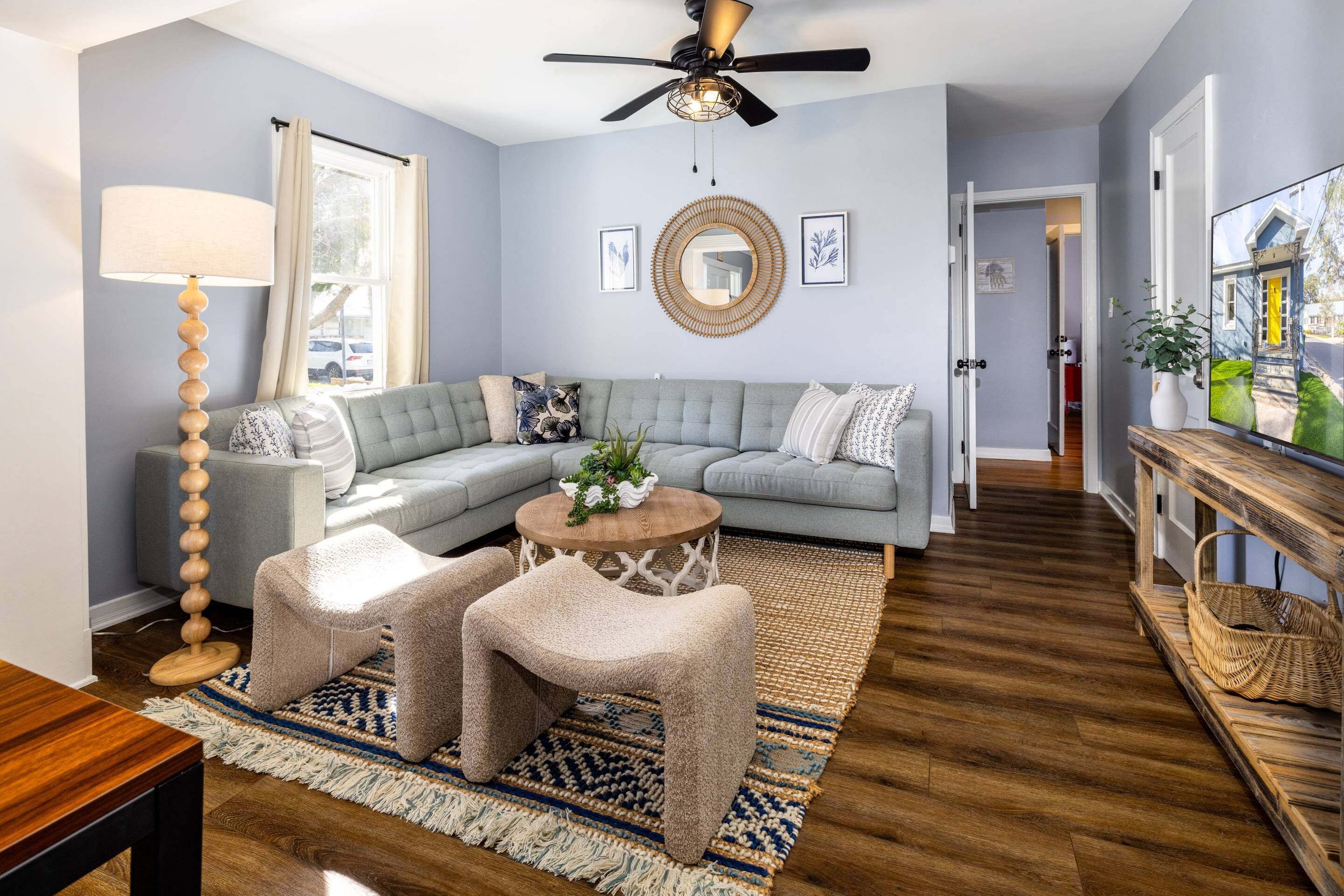 A modern living room with a sectional sofa, a round coffee table, and a ceiling fan.