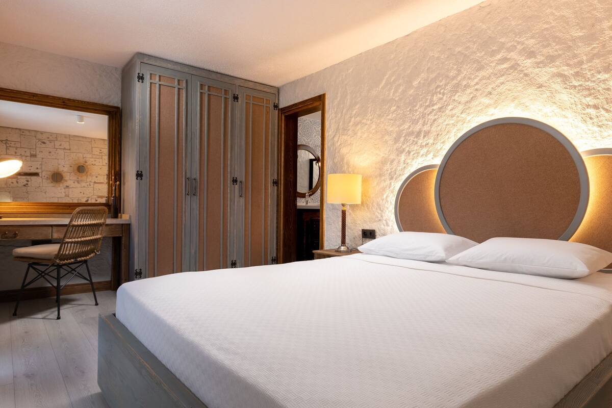 A hotel room with a bed, a desk, and a chair.