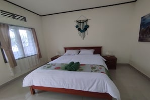 A neatly made bed with white bedding and green towels, a bedside table with a lamp, and a wall-mounted decorative item. - SPOT ON 93739 Insanta Hotel Near Masjid Baitul Aman (Senggigi)