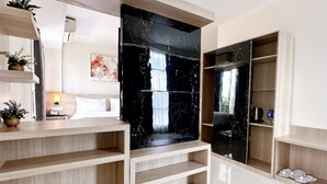 A modern hotel room with a large black marble accent wall, wooden shelving, and a flat-screen TV. - Aimas Hotel & Convention Centre (Sorong)