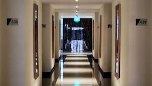 A hotel corridor with a polished floor, framed pictures on the walls, and numbered doors. - Aimas Hotel & Convention Centre (Sorong)