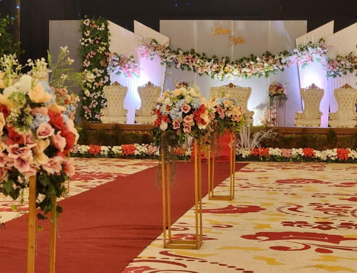 A stage with floral decorations and a red carpet, likely for a formal event.
