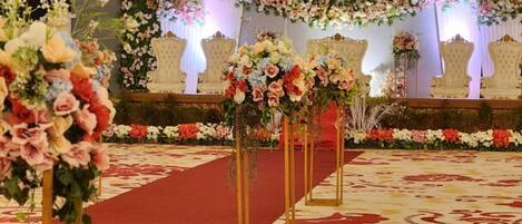 A stage with floral decorations and a red carpet, likely for a formal event.