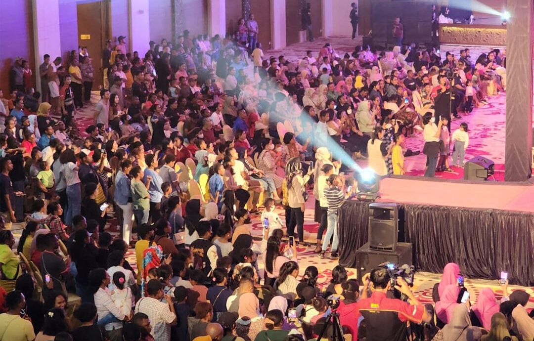 A crowded indoor event with a stage and audience.